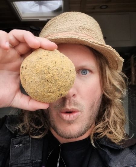 man holding vegan scotch egg to his eye