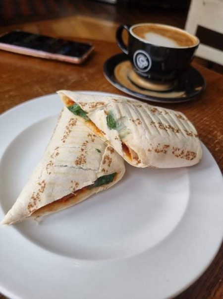 vegan meatball wrap next to a cup of coffee
